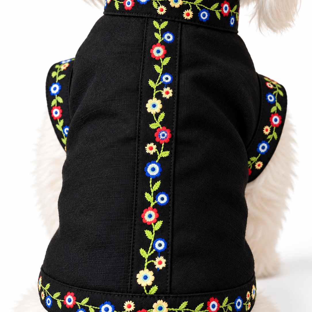 A black dog sweater with colorful floral embroidery, shown on a small white dog from behind against a white background.