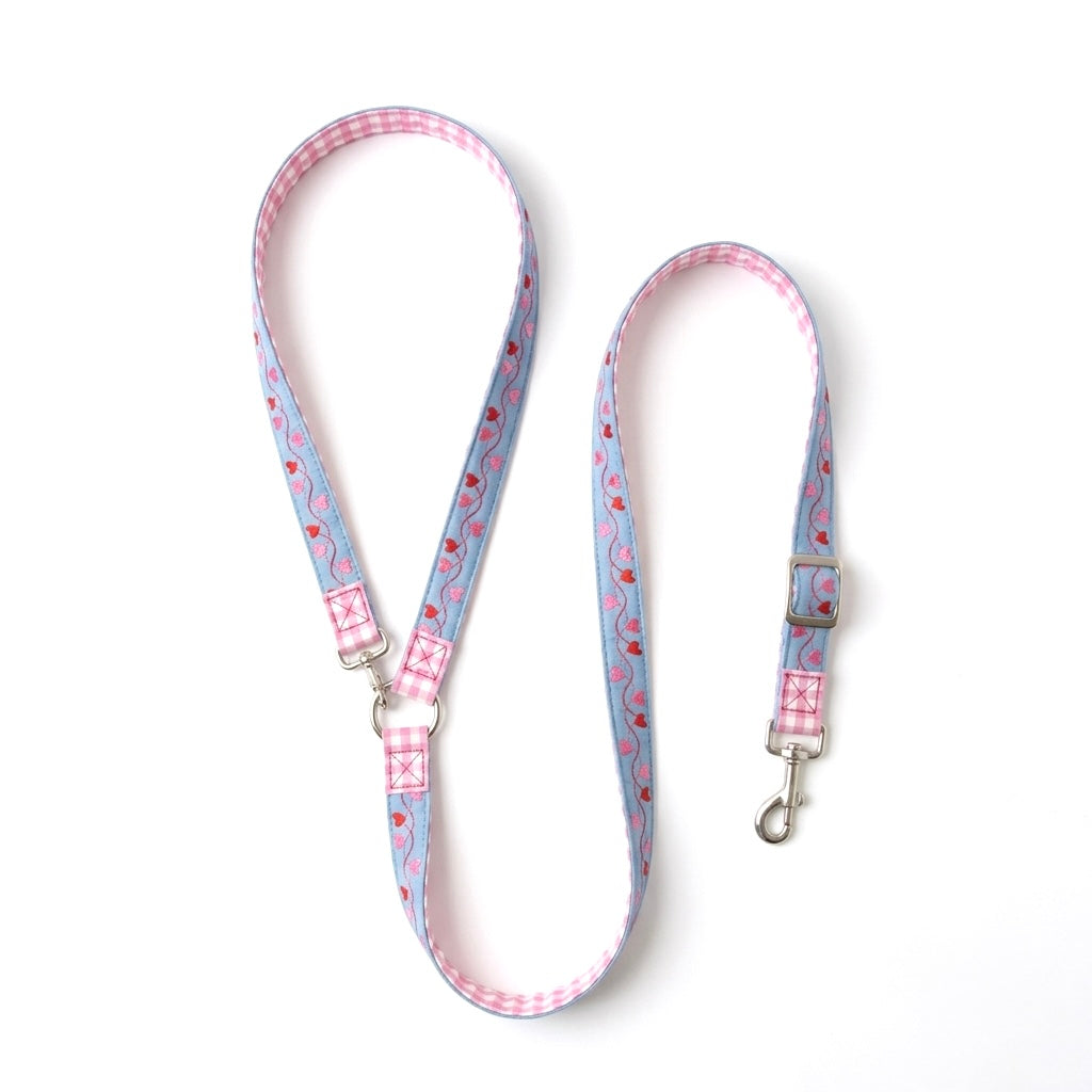 A light blue dog leash with a pink and white gingham border, a pink and red strawberry pattern, and silver metal hardware, displayed on a clean white background.