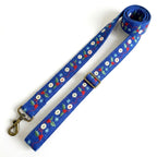 A blue dog leash with a festive embroidered pattern of red berries, green leaves, white snowflakes, and blue snowdrops, featuring brass hardware on a white background.