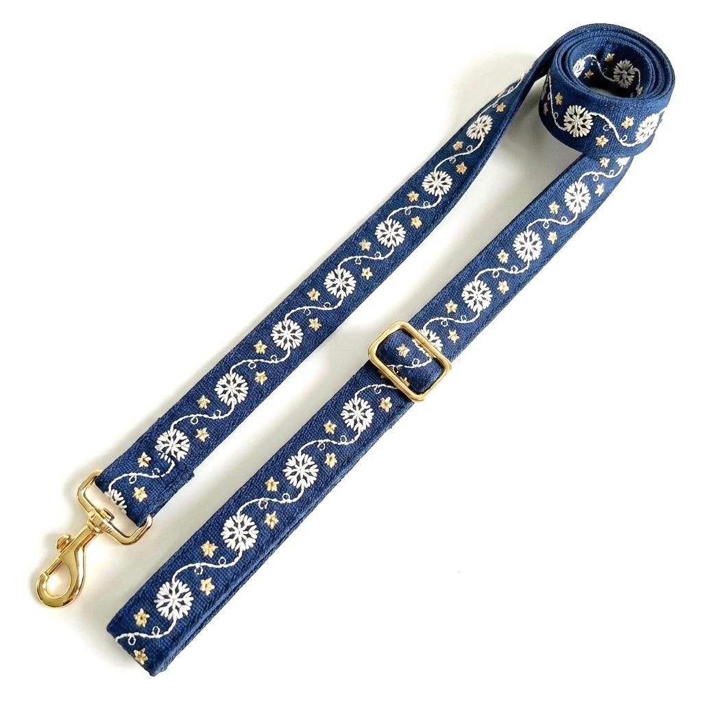 A navy blue dog leash with a white floral and vine pattern and gold-tone hardware, including a swivel snap hook and adjustment buckle, shown on a plain white background.