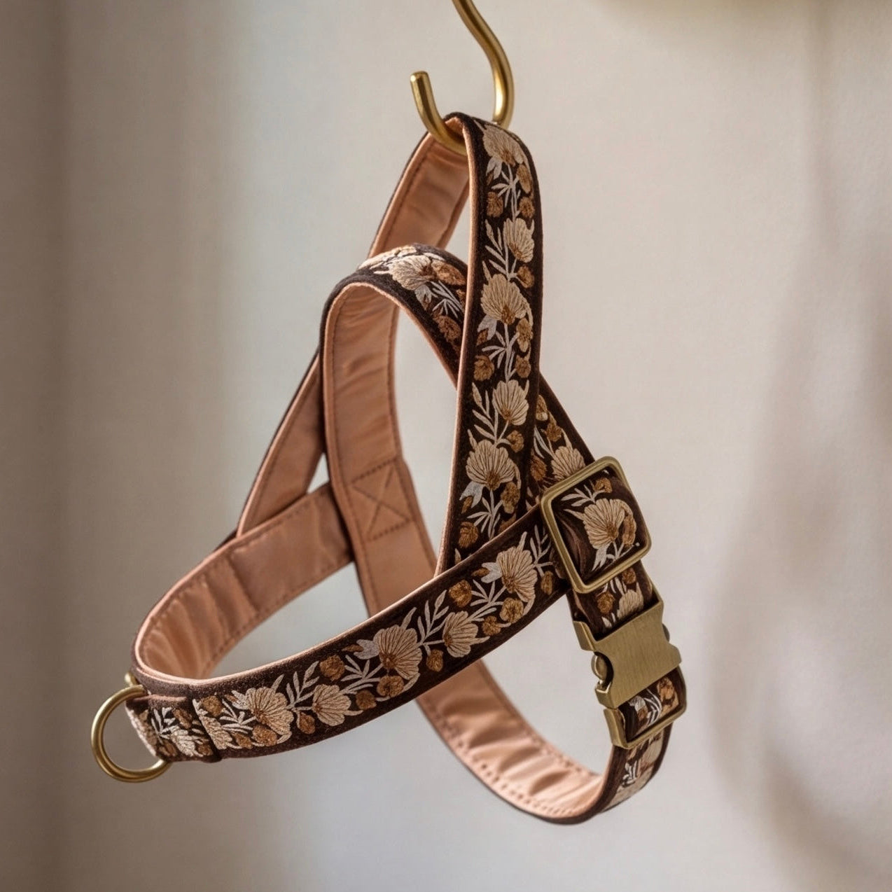 Dog harness with floral embroidery on a hanger against a neutral background