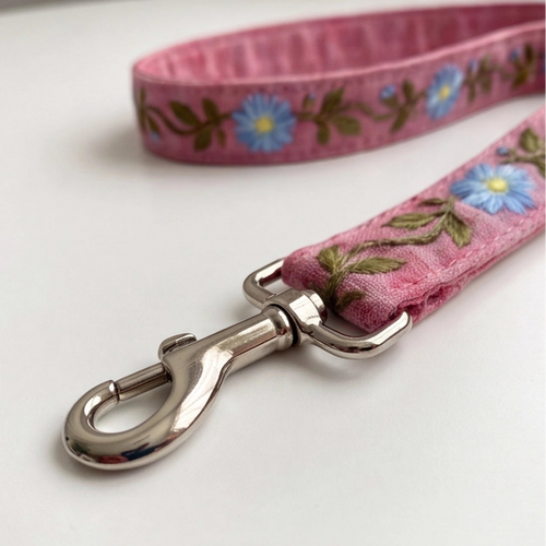 Pink floral dog leash with a metal clip on a white background