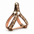 A dog harness with a brown floral embroidered pattern, a peach satin inner lining, and brass hardware, shown on a white background.