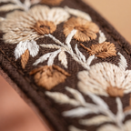 Close-up of an embroidered fabric with floral patterns on a brown fabric
