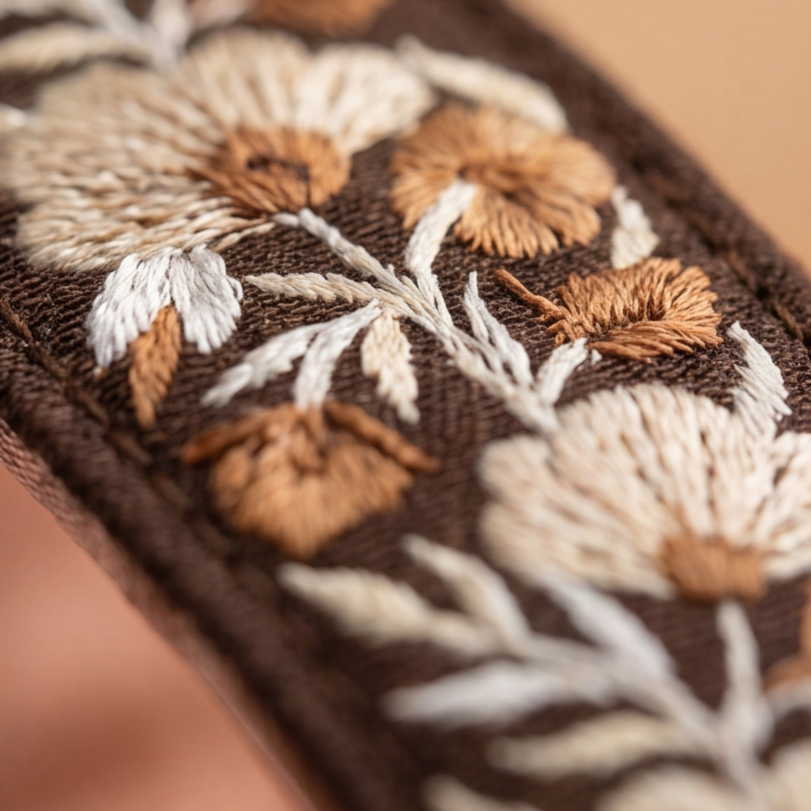 Close-up of an embroidered fabric with floral patterns on a brown fabric