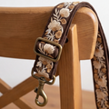 Floral-patterned dog leash with brass hardware on a wooden chair.