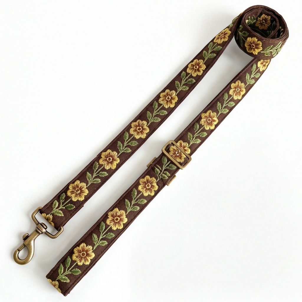 A floral-patterned leash with antique metal hardware on a white background
