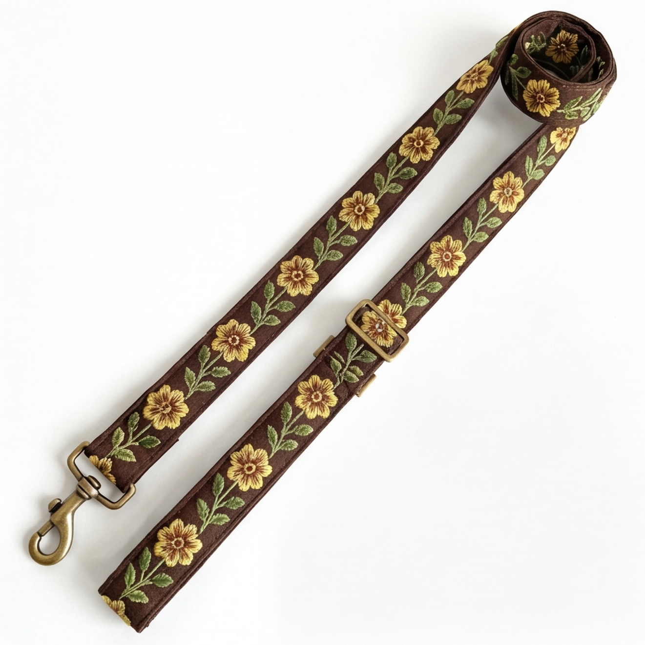 A floral-patterned leash with antique metal hardware on a white background