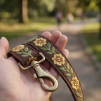 Floral embroidered leash held in a hand with a park background