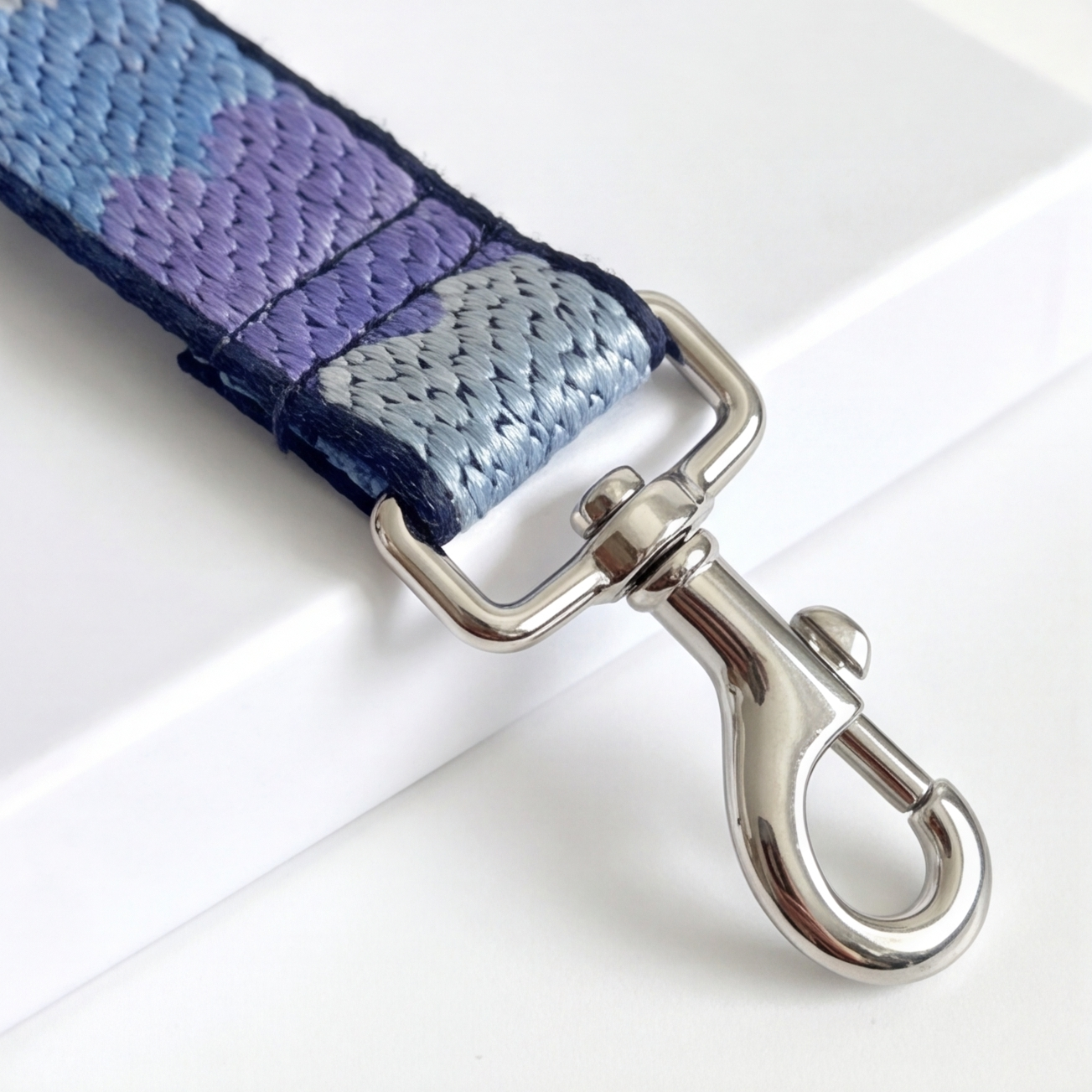 Leash with purple and blue pattern and silver dog hook on a white background