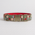 A dog collar with a sage green embroidered fabric exterior, featuring red berries, green leaves, and blue snowflake motifs, a bright red interior, and a brass-tone buckle.