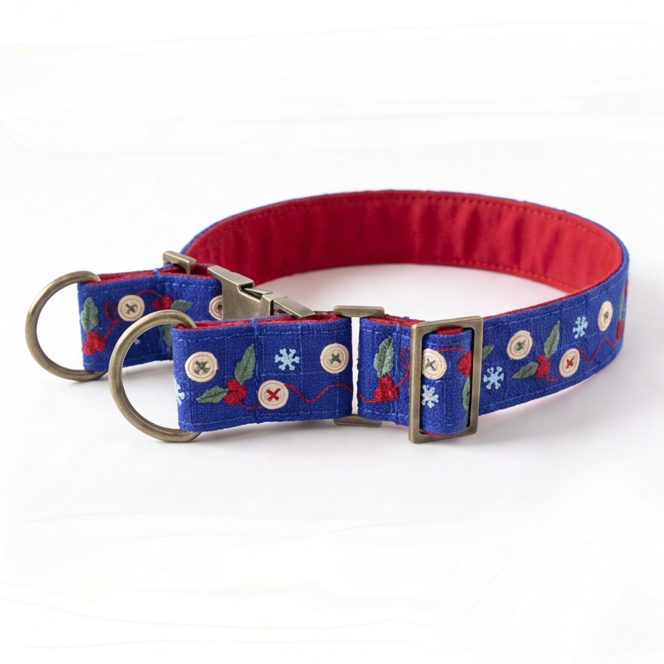A blue fabric dog collar with a red interior lining, decorated with embroidered white flowers, red berries, and green leaves. It features a silver-tone metal buckle, a matching D-ring, and a quick-release clasp, shown on a plain white background.