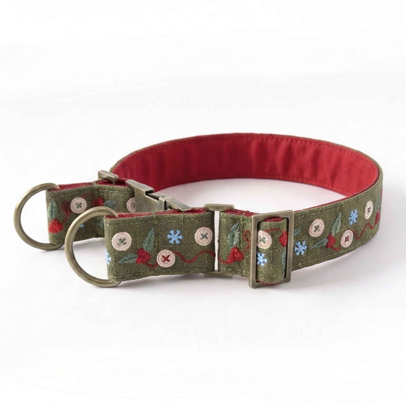 A dog collar with an olive green embroidered fabric exterior featuring holiday motifs like pine trees, snowflakes, and buttons, and a contrasting red fabric lining.
