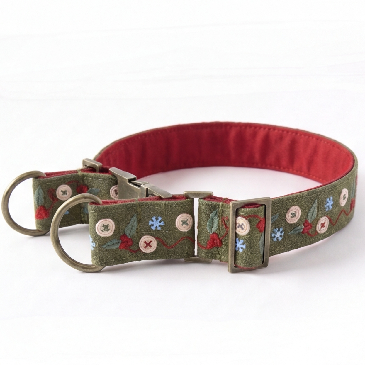 A green embroidered dog collar with a red interior lining, featuring decorative floral and snowflake patterns, brass hardware, and a red D-ring, shown on a white background.