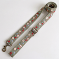 An embroidered dog leash strap, likely a dog leash or bag strap, featuring a sage green base with floral embroidery in red, light blue, and white. It has a metal buckle and a brass-colored swivel clasp, shown on a plain light background.
