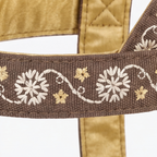Close-up of a brown woven strap with embroidered white and beige floral patterns, attached to a gold satin strap on a white background.
