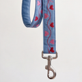 A light blue denim-style strap with embroidered red and pink hearts and wavy lines, finished with a silver metal swivel clasp, shown against a plain light background.