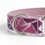 A close-up of a pink and purple patterned fabric collar with a silver metal D-ring and buckle, shown on a white background.