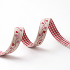 A decorative fabric ribbon with a red and white gingham checkered pattern on one side and a cream background with embroidered pink and red hearts and vines on the other, shown coiled on a white background.