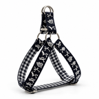 A triangular dog harness with black and white gingham fabric straps, featuring white dog silhouettes printed on the black outer bands, and silver metal hardware.